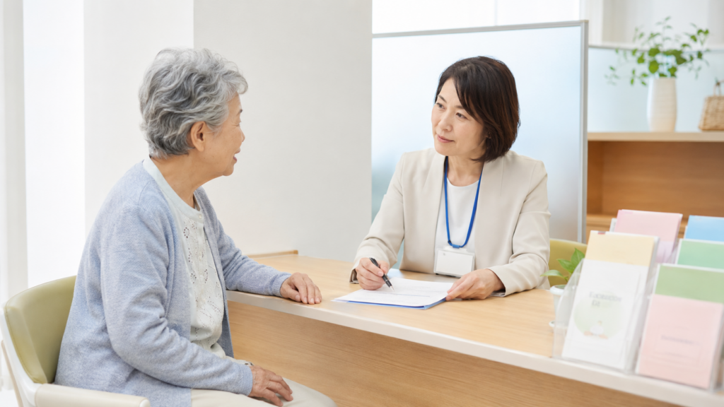 地域包括支援センターの窓口で相談する高齢の女性と職員